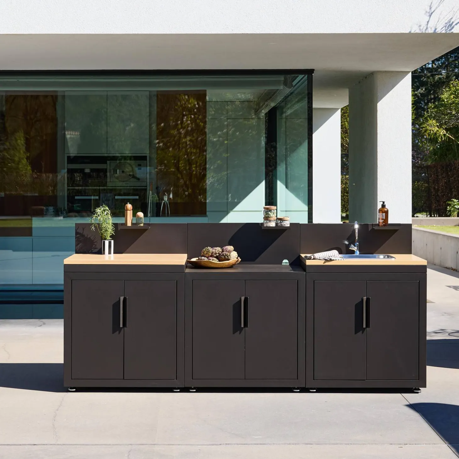 Cozinha exterior com 3 módulos em aço e decoração em madeira