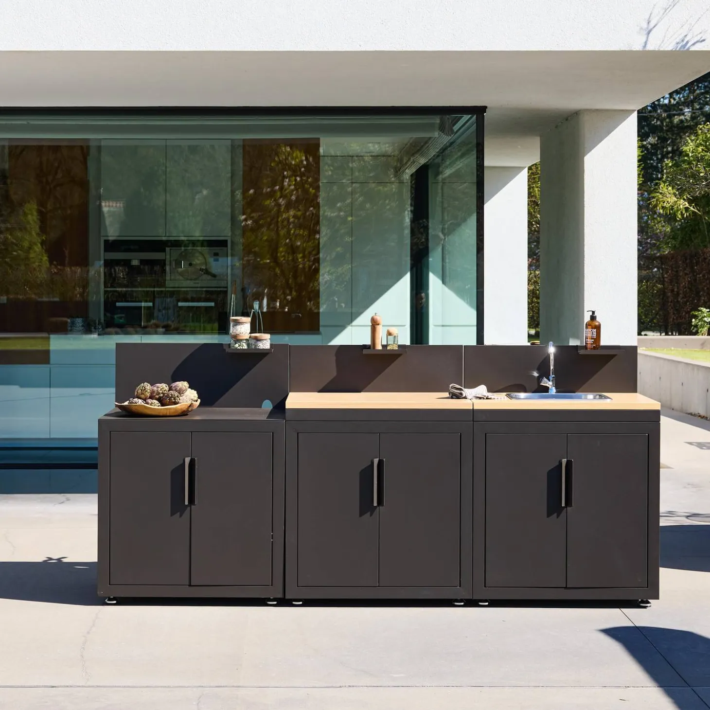 Cozinha exterior com 3 módulos em aço e decoração em madeira